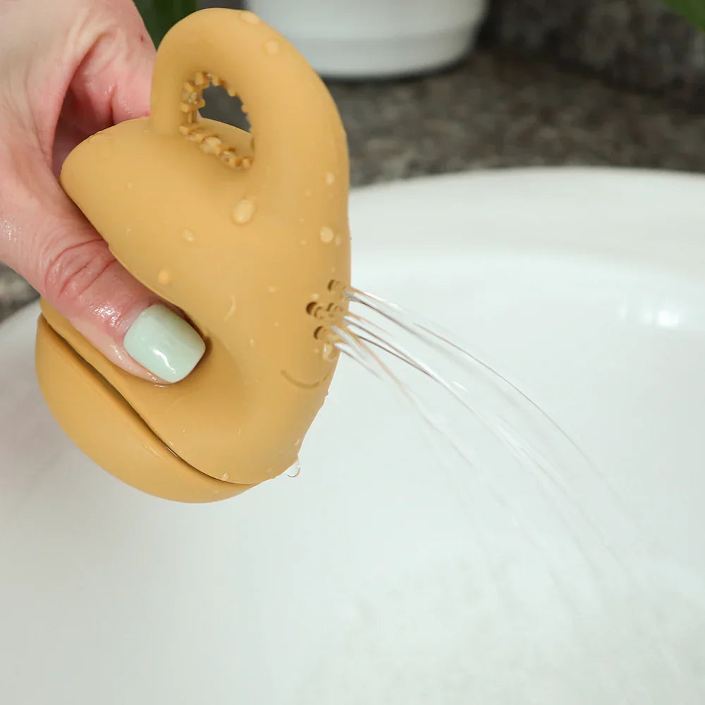Juguete de baño de silicona amarillo vertiendo agua a través de orificios.
