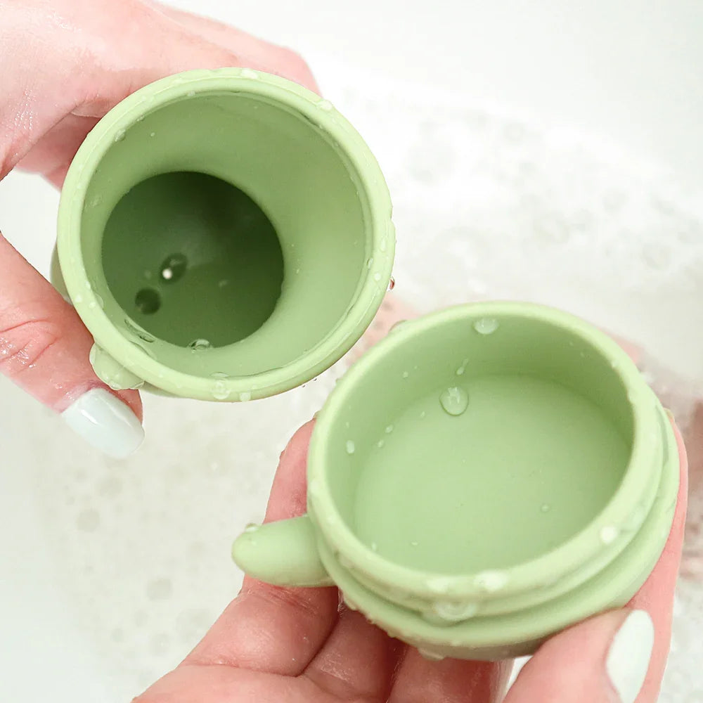 Juguete de baño de silicona verde dividido en dos piezas para limpieza.