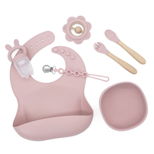 Set Summer de silicona color rosa empolvado con babero, bowl, cuchara y tenedor de madera, feeder con orejitas y mordedor de flor.