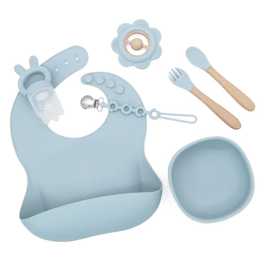 Set Summer de silicona color azul empolvado con babero, bowl, cuchara y tenedor de madera, feeder con orejitas y mordedor de flor.